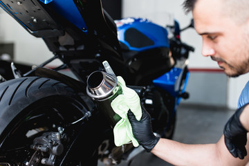 A man cleaning motorcycle with cloth. Selective focus. 