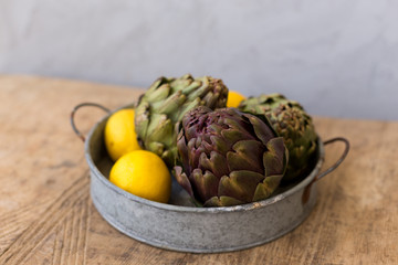 Healthy lifestyle concept. Artichokes and lemons in round metal