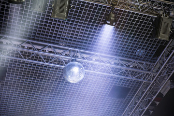 Silver mirror disco ball in the rays of the spotlights