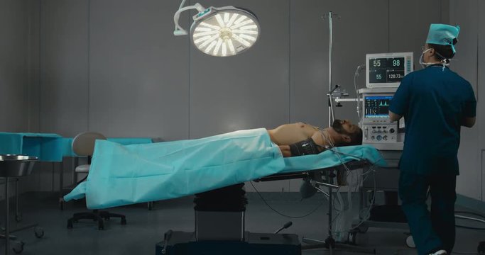 DOLLY IN WIDE male anesthetist preparing operating theatre for operation. 4K UHD 60 FPS SLO MO