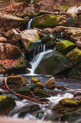 Fototapeta na wymiar Beautiful mountain waterfalls with long exposure in golden spring sunlight. Ilsefälle of the mountain river Ilse in the Ilsetal in Ilsenburg, National Park Harz, Saxony-Anhalt in Germany