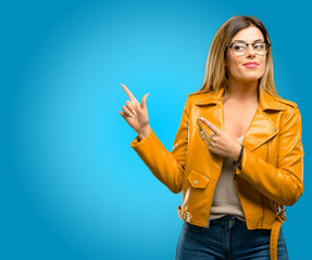 Beautiful young woman pointing away side with fingers, blue background