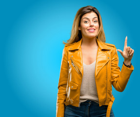 Beautiful young woman pointing away side with finger, blue background