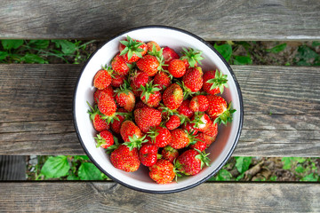 Plate full of fresh ripe red strawberries on a wood background