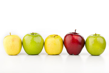 Multicolored apples in a row on a white table