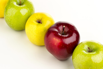Multicolored apples in a row on a white table