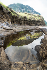 Obraz premium Natural pool with view on Mount Sanbangsan of Yongmeori Beach, Sanbang-ro, Jeju Island, South Korea, vertical