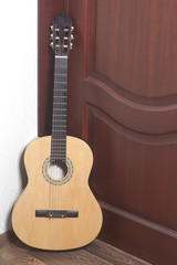 Acoustic guitar leaning against a wooden door