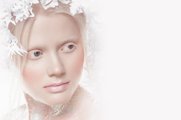 A very delicate portrait of an albino girl, a white background, snowflakes in her hair, sparkles, a magical winter image. Natural make-up, pink lipstick on lips.