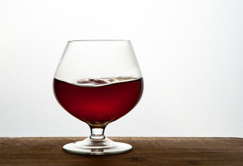 Glass of brandy or cognac on the wooden and white background with copy space
