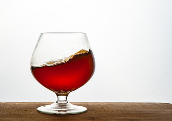 Glass of brandy or cognac on the wooden and white background with copy space