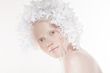 A very delicate portrait of an albino girl, a white background, snowflakes in her hair, sparkles, a magical winter image. Natural make-up, pink lipstick on lips.