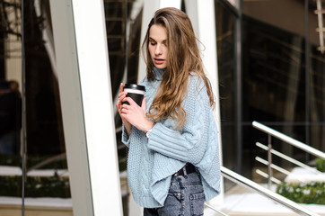 Young attractive lady with long curly hair with coffee to go, wearing stylish clothes 