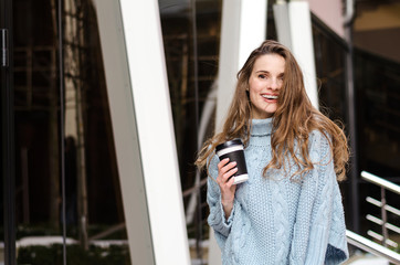 Fototapeta premium Young attractive lady with long curly hair with coffee to go, wearing stylish clothes 