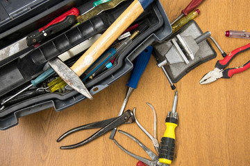 open toolbox, small portable vice screwdriver tools for repair  randomly scattered on the work surface