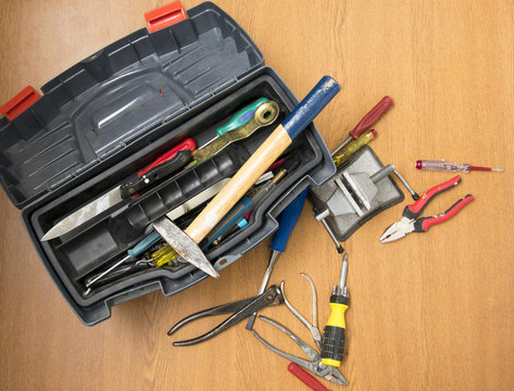 open toolbox, small portable vice screwdriver tools for repair  randomly scattered on the work surface