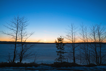 Frozen lake in the forest at sunset in the spring.