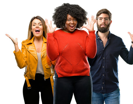 Group of three young men and women happy and surprised cheering expressing wow gesture