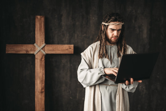 Man in the image of Jesus Christ uses laptop