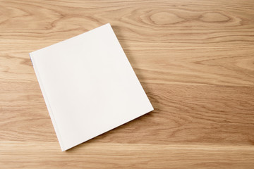 Blank white magazine cover on wooden table background.