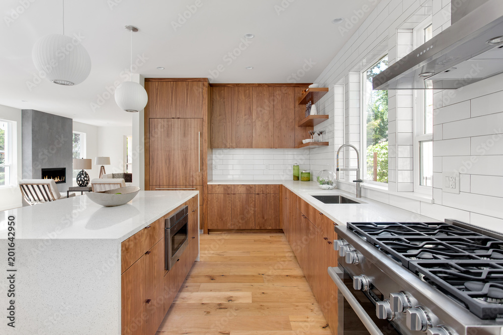 Wall mural Beautiful kitchen in new home with brown hardwood cabinets, white subway tile, and hardwood floors. 