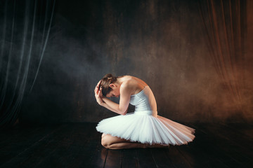Fototapeta premium Ballerina in white dress sitting on stage