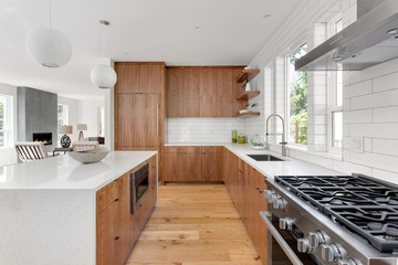 Beautiful kitchen in new home with brown hardwood cabinets, white subway tile, and hardwood floors. 