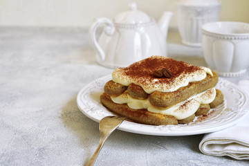 Portion of tiramisu cake on a white vintage plate.