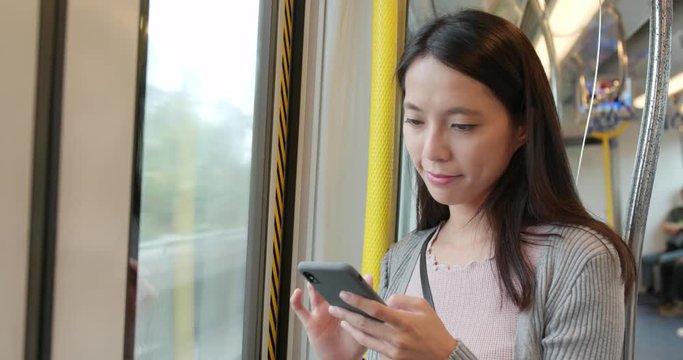 Woman using smart phone on train compartment