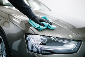 A man cleaning car with microfiber cloth, car detailing (or valeting) concept. Selective focus. 