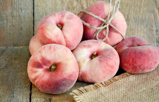 Saturn peach or Dough nut peaches on wooden background and sack cloth