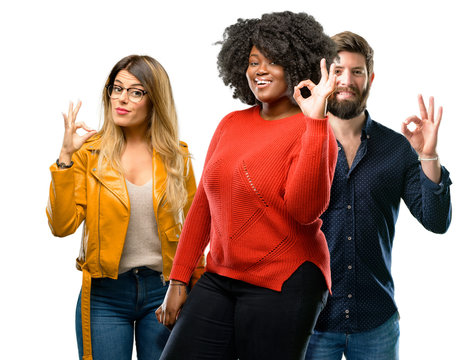 Group of three young men and women doing ok sign with hand, approve gesture