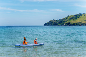 Fototapeta na wymiar Two little children canoeing at tropical beach