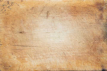 A textured wooden cutting board. Close-up view from top. Free space for text.