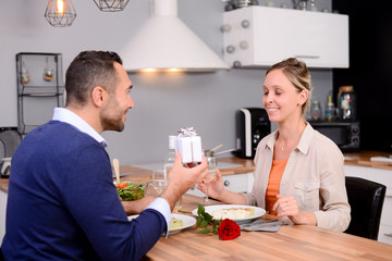 beautiful couple man and woman offering a gift during a love romantic valentine dinner together at home eyes closed