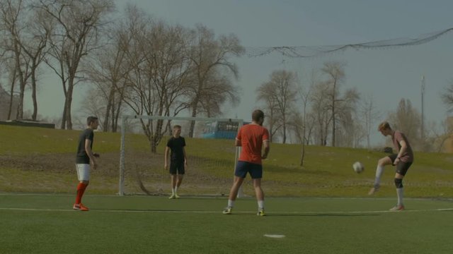 Skillful young soccer player performing bicycle kick and scoring a goal during football training on sports field. Positive footballers playing game and striker executing bicycle kick on soccer field.