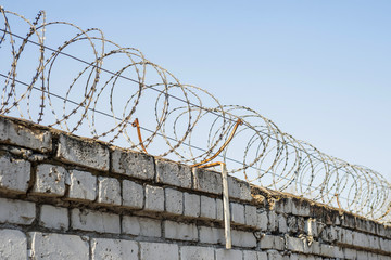 Barbed wire wound to the top of a brick fence