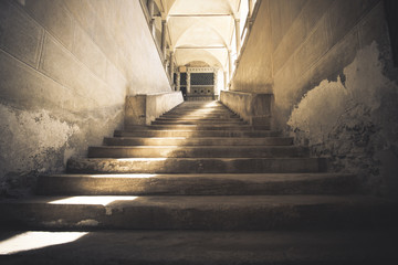 dark stairway made of stone, uphill and with a ray of sunshine t