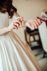 Close up of the bride's hands in a wedding dress sprinkle perfume on the wrist, vertical