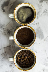 Three cups of coffee at different stages of cooking. Ground coffee, coffee beans and ready-made coffee drink. Top view, flat lay