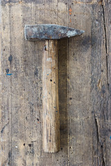 Old, dirty hammer against wooden plank. Tool series.