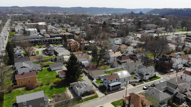 A daytime late winter slow forward aerial establishing shot of a typical residential neighborhood in a Western Pennsylvania small town. Pittsburgh suburbs.  	