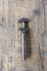 Old, dirty screw press against wooden plank. Tool series.