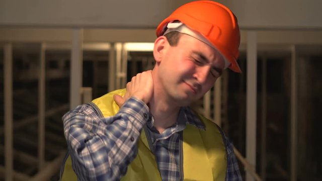 On a construction site, a worker or engineer or architect with neck pain