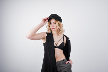 Studio portrait of blonde girl in black wear and cap against white background.