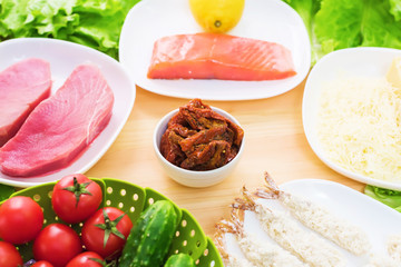 Raw appetizing fillet of tuna on a table with a yard of Greek salad with salmon and lemon cucumbers and tomatoes as well as cheese. The concept of a delicious and healthy home-made meal