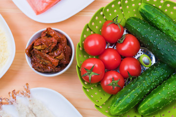 Still life of raw food in white plates on a wooden table. Frozen salmon on a plate next to cucumbers and tomatoes grated cheese and raw shrimps in breaded. Background for the theme of healthy eating