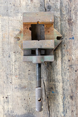 Old, dirty screw press against wooden plank. Tool series.