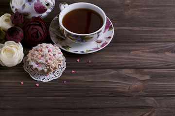 Teapot tea cup and cake on brown wooden table.