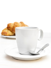 Cup of coffee with croissants on the white wooden table. Isolated on white.